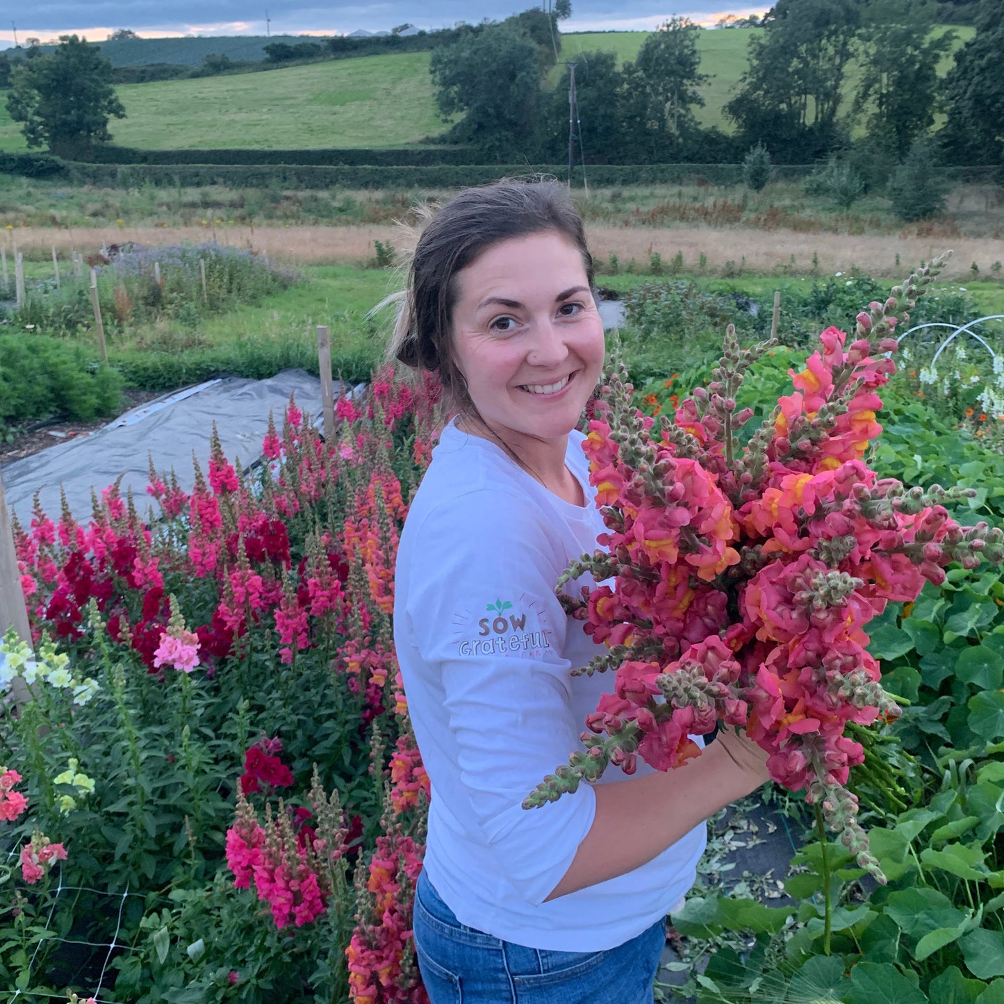 Person holding a bundle of pink flowers in a garden setting